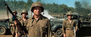 Movie still from “Kelly's Heroes” (1970), directed by Brian G. Hutton – A group of men standing next to each other in front of a truck; Medium shot, Over the shoulder angle