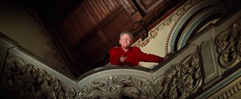 Movie still from “Kelly's Heroes” (1970), directed by Brian G. Hutton – A man in a red jacket standing on a staircase; Medium shot, Low angle