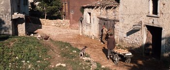 Movie still from “Kelly's Heroes” (1970), directed by Brian G. Hutton – Two men and a dog in front of an old building; Extreme Wide shot, High angle