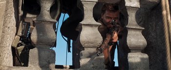 Movie still from “Kelly's Heroes” (1970), directed by Brian G. Hutton – A man with a gun is looking through a hole in a wall; Medium shot, Low angle