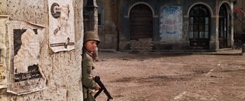 Movie still from “Kelly's Heroes” (1970), directed by Brian G. Hutton – A man in a military uniform holding a gun; Wide shot, Over the shoulder angle
