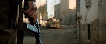 Movie still from “Kelly's Heroes” (1970), directed by Brian G. Hutton – A person holding a gun in front of a tank; Extreme Close Up shot, High angle