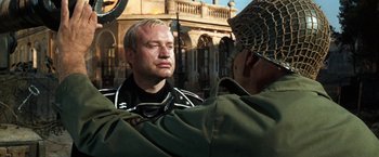 Movie still from “Kelly's Heroes” (1970), directed by Brian G. Hutton – A man in a military uniform looking at another man in fatigues; Medium shot, Over the shoulder angle