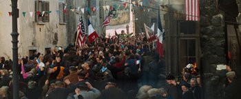 Movie still from “Kelly's Heroes” (1970), directed by Brian G. Hutton – A crowd of people walking down a street with flags; Wide shot, High angle