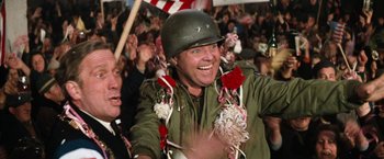 Movie still from “Kelly's Heroes” (1970), directed by Brian G. Hutton – A man in a military uniform is smiling and wearing a helmet; Medium shot, Over the shoulder angle
