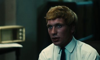 Movie still from “Kes” (1969), directed by Ken Loach – A man with blonde hair wearing a white dress shirt and tie; Close Up shot, High angle