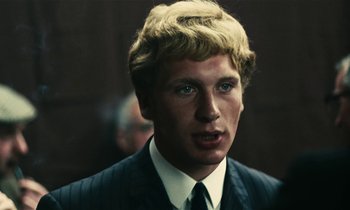 Movie still from “Kes” (1969), directed by Ken Loach – A man in a suit and tie looking at the camera; Close Up shot, Over the shoulder angle