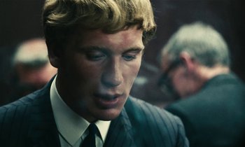 Movie still from “Kes” (1969), directed by Ken Loach – A man in a suit and tie looking down; Close Up shot, Over the shoulder angle