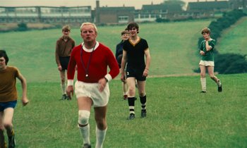 Movie still from “Kes” (1969), directed by Ken Loach – A group of young men playing a game of soccer on a field; Wide shot, High angle