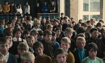 Movie still from “Kes” (1969), directed by Ken Loach – A large group of young people in a room; Wide shot, High angle