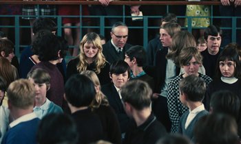 Movie still from “Kes” (1969), directed by Ken Loach – A group of people standing around each other in a room; Medium shot, High angle