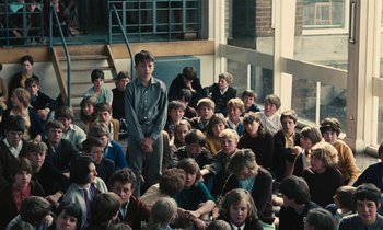 Movie still from “Kes” (1969), directed by Ken Loach – A large group of people sitting on the steps of a building; Wide shot, High angle