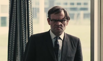 Movie still from “Kes” (1969), directed by Ken Loach – A man in a suit and tie standing in front of a window; Close Up shot, Low angle