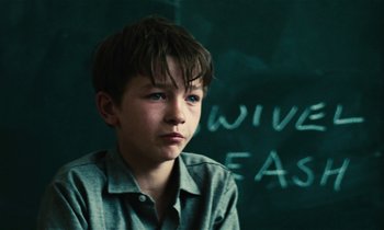 Movie still from “Kes” (1969), directed by Ken Loach – A young boy sitting in front of a chalkboard; Close Up shot, Over the shoulder angle