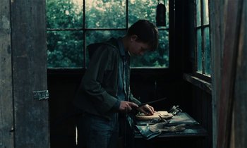 Movie still from “Kes” (1969), directed by Ken Loach – A young man cutting a piece of wood with a knife; Medium shot, High angle