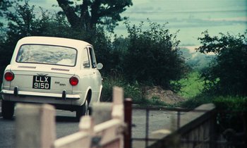 Movie still from “Kes” (1969), directed by Ken Loach – A white car is driving down the street; Wide shot, High angle