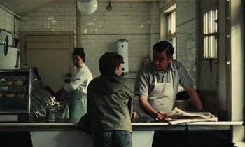 Movie still from “Kes” (1969), directed by Ken Loach – A man and a boy in a kitchen preparing a meal; Medium shot, Over the shoulder angle