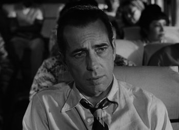 Movie still from “Key Largo” (1948), directed by John Huston – Black and white photograph of a man in a tie; Close Up shot, Over the shoulder angle