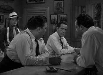 Movie still from “Key Largo” (1948), directed by John Huston – A group of men sitting at a table in a room; Medium shot, Over the shoulder angle