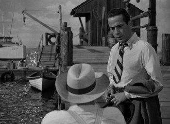 Movie still from “Key Largo” (1948), directed by John Huston – A black and white photo of a man and a woman; Medium shot, Over the shoulder angle