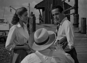 Movie still from “Key Largo” (1948), directed by John Huston – A black and white photo of a man and a woman talking; Medium shot, Over the shoulder angle