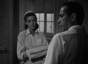Movie still from “Key Largo” (1948), directed by John Huston – A man and a woman are standing in front of a window; Medium shot, Over the shoulder angle
