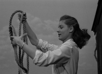 Movie still from “Key Largo” (1948), directed by John Huston – A woman holding onto a rope while standing on a ledge; Medium shot, Low angle