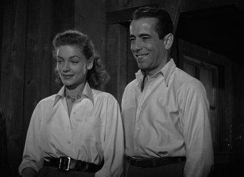 Movie still from “Key Largo” (1948), directed by John Huston – A black and white photo of a man and a woman standing next to each other; Medium shot, Low angle
