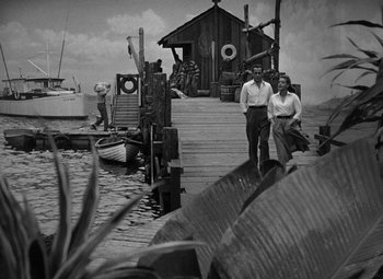 Movie still from “Key Largo” (1948), directed by John Huston – A man and a woman walking on a dock; Wide shot, High angle
