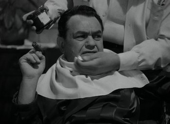 Movie still from “Key Largo” (1948), directed by John Huston – An old photo of a man getting a haircut; Close Up shot, Over the shoulder angle
