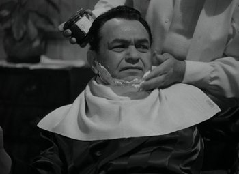 Movie still from “Key Largo” (1948), directed by John Huston – A man getting his hair cut by a barber; Close Up shot, Over the shoulder angle