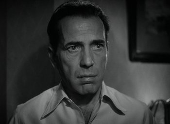 Movie still from “Key Largo” (1948), directed by John Huston – Black and white photograph of a man in a white shirt; Close Up shot, Low angle