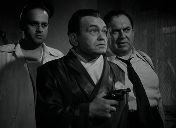 Movie still from “Key Largo” (1948), directed by John Huston – A group of men standing next to each other holding guns; Medium shot, Low angle