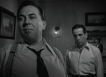 Movie still from “Key Largo” (1948), directed by John Huston – A black and white photo of two men standing next to each other; Close Up shot, Low angle