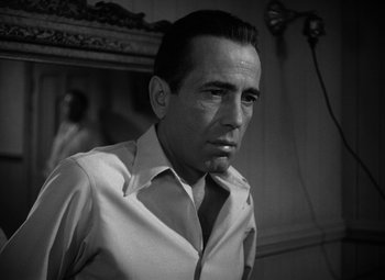 Movie still from “Key Largo” (1948), directed by John Huston – Black and white photograph of a man in a shirt and tie; Close Up shot, Low angle