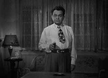 Movie still from “Key Largo” (1948), directed by John Huston – A black and white photo of a man holding a knife; Medium shot, Low angle