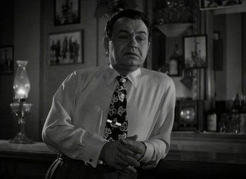 Movie still from “Key Largo” (1948), directed by John Huston – An older man wearing a tie in front of a wall; Close Up shot, Low angle