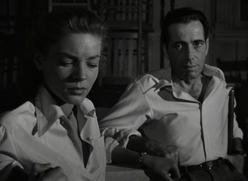 Movie still from “Key Largo” (1948), directed by John Huston – A man and a woman sitting next to each other; Medium shot, Low angle