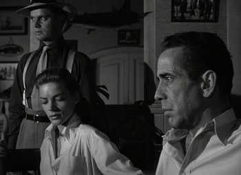 Movie still from “Key Largo” (1948), directed by John Huston – A black and white photo of two men and a woman; Medium shot, Over the shoulder angle