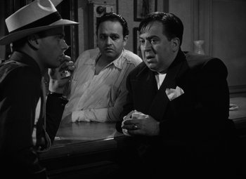 Movie still from “Key Largo” (1948), directed by John Huston – A group of men sitting at a table in a room; Medium shot, Over the shoulder angle