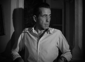 Movie still from “Key Largo” (1948), directed by John Huston – Black and white photograph of a man in a white dress shirt; Close Up shot, Low angle