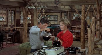 Movie still from “Kid Galahad” (1962), directed by Phil Karlson – A man and a woman pouring something into a wine glass; Wide shot, High angle