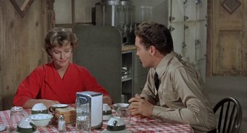 Movie still from “Kid Galahad” (1962), directed by Phil Karlson – A man and a woman sitting at a table; Medium shot, Over the shoulder angle