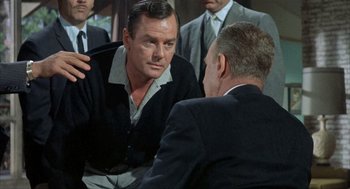 Movie still from “Kid Galahad” (1962), directed by Phil Karlson – A man talking to another man in front of a group of men; Medium shot, Over the shoulder angle