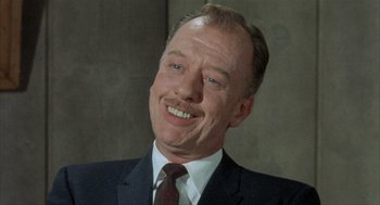 Movie still from “Kid Galahad” (1962), directed by Phil Karlson – An older man wearing a suit and tie smiling; Close Up shot, Low angle
