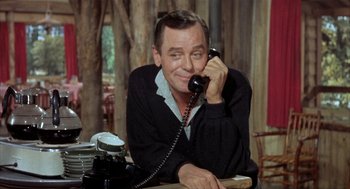 Movie still from “Kid Galahad” (1962), directed by Phil Karlson – A man sitting at a table talking on a phone; Medium shot, Low angle