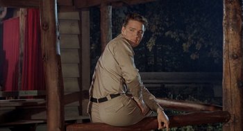 Movie still from “Kid Galahad” (1962), directed by Phil Karlson – A man sitting on top of a wooden railing; Medium shot, Low angle