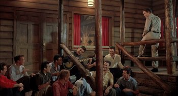 Movie still from “Kid Galahad” (1962), directed by Phil Karlson – A group of men sitting in a room with a guitar; Wide shot, Low angle