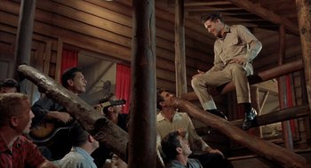 Movie still from “Kid Galahad” (1962), directed by Phil Karlson – A group of men sitting on top of a wooden pole; Wide shot, Low angle