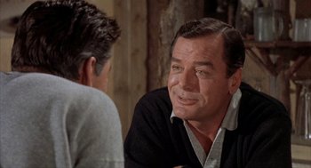 Movie still from “Kid Galahad” (1962), directed by Phil Karlson – A man sitting next to another man in front of a wooden wall; Close Up shot, Over the shoulder angle